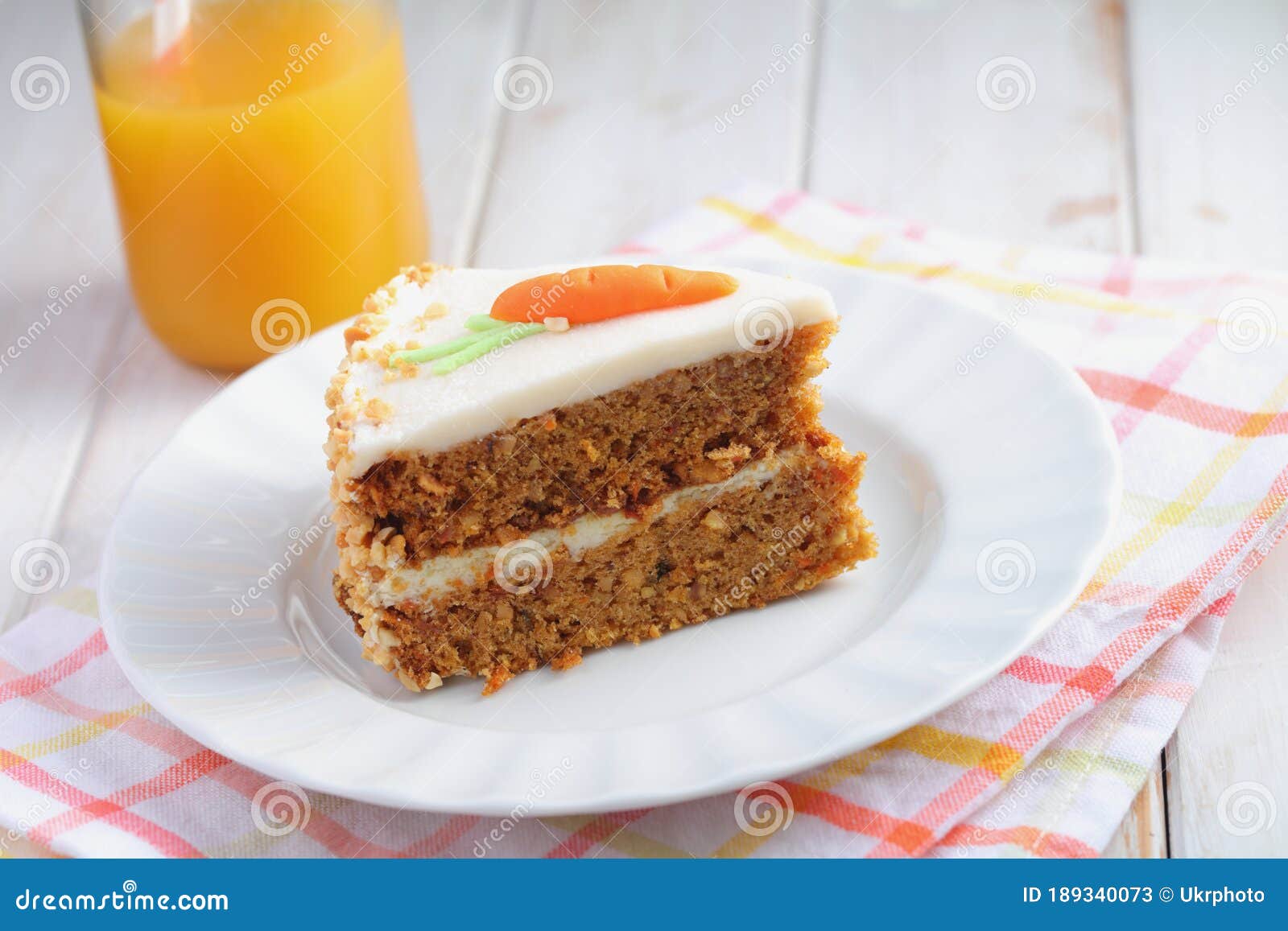 slice of carrot cake  pastel de zanahoria with icing and marzipan carrot on white background with carrot juice