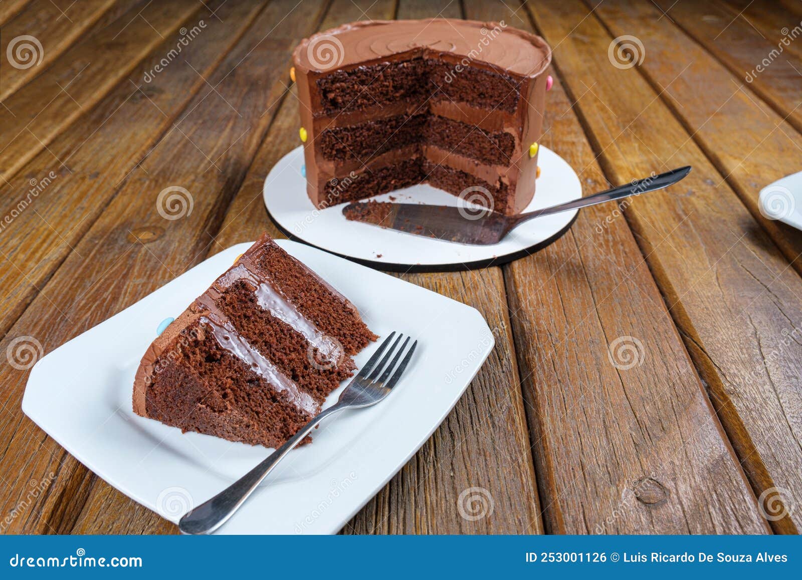 slice of chocolate cake with filling and semisweet chocolate ganache frosting. next to the sliced cake_side view