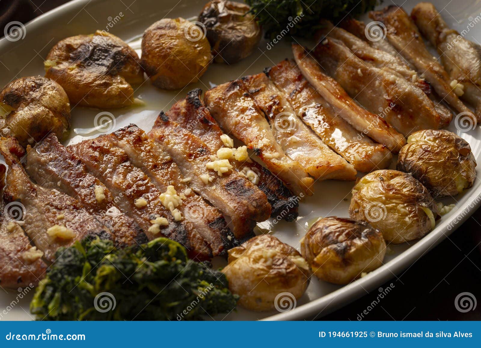 sliced black pig meat `secretos de porco preto` with smashed potatoes and turnip greens, a typical iberian plate.