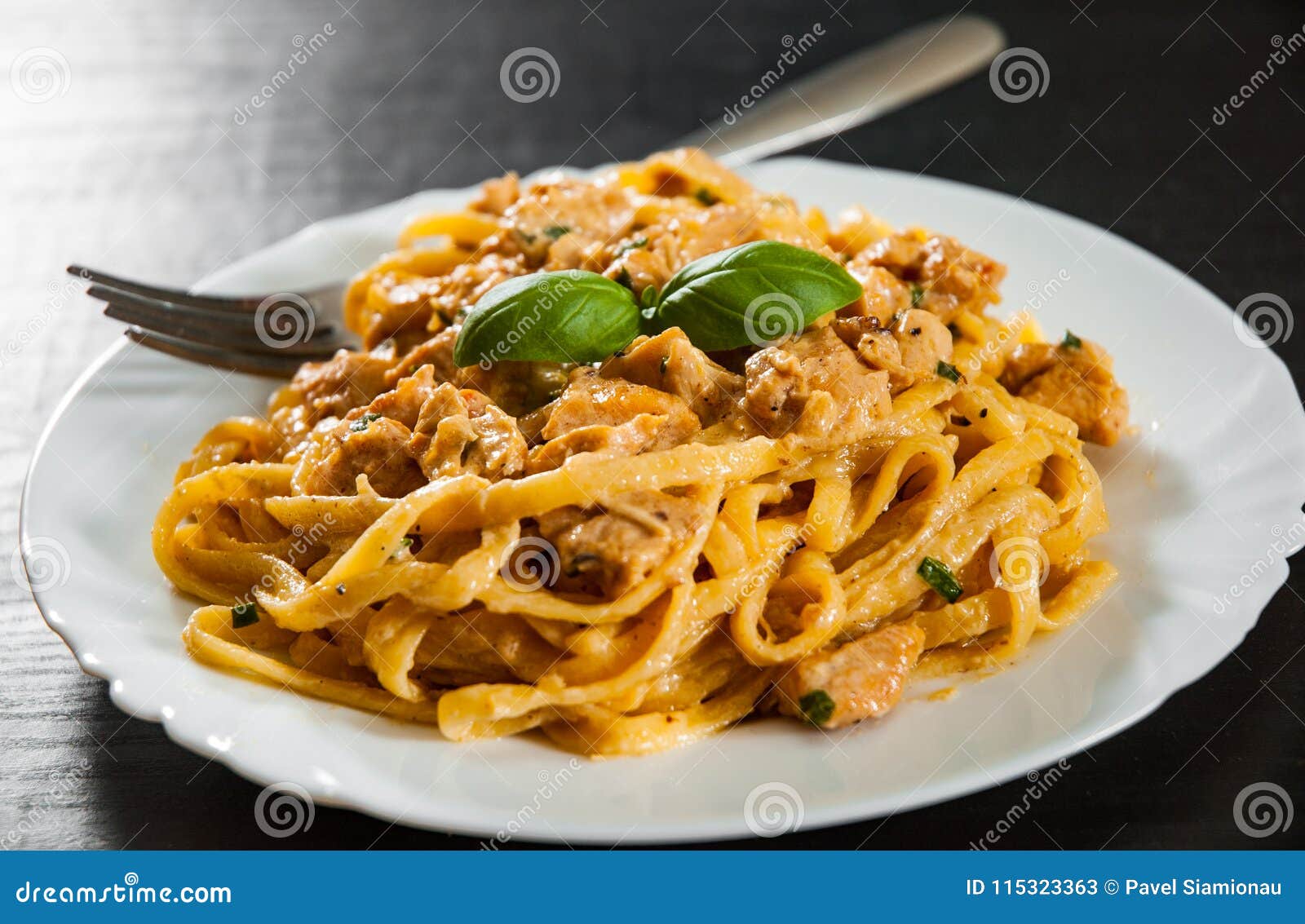 sliced fried chicken breast meat in a creamy sauce with bavette pasta in a plate
