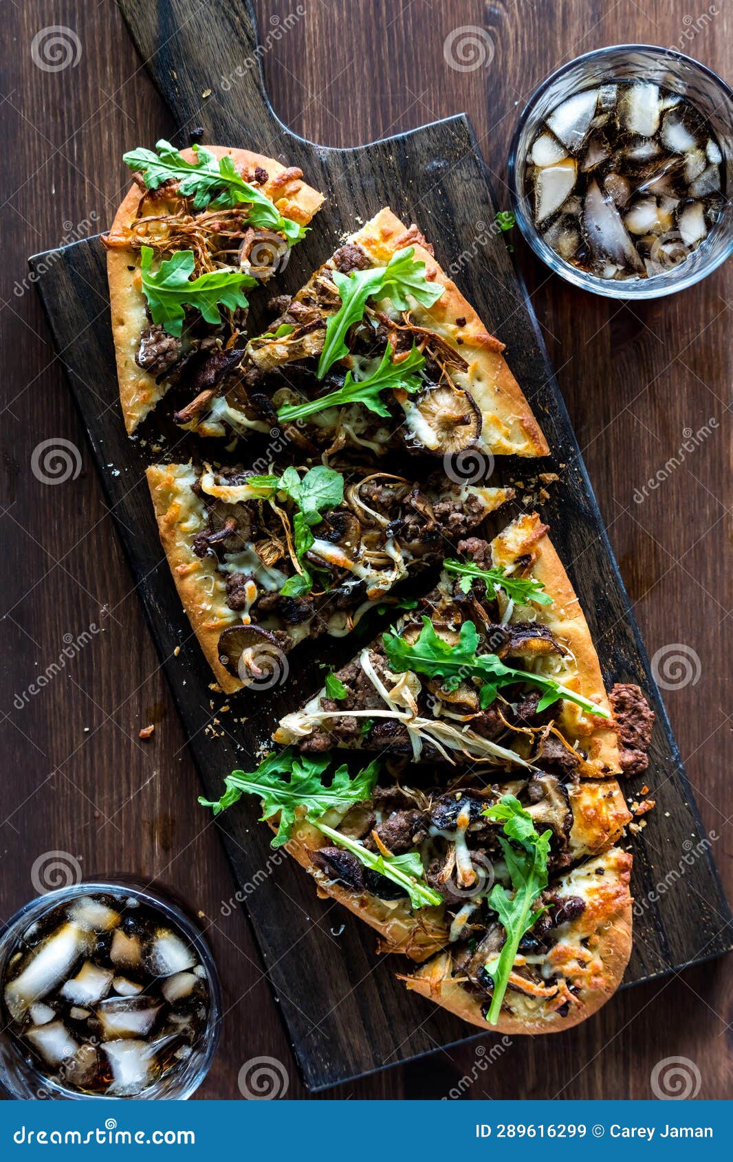 A Sliced Mushroom and Beef Flatbread Pizza Served with Cola for