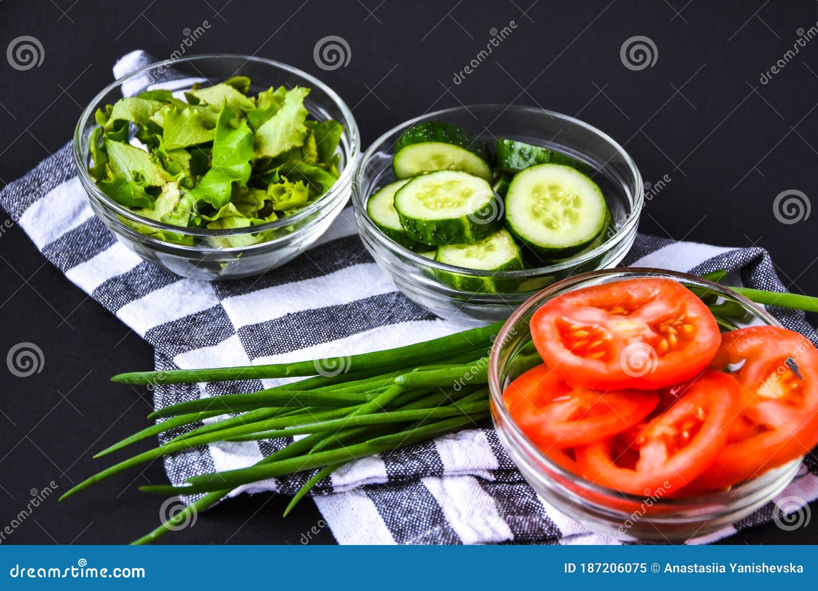 sliced raw cucumbers tomatoes letture and green onion in bowls, prepared for vegan healthy salad, detox low calorie diet