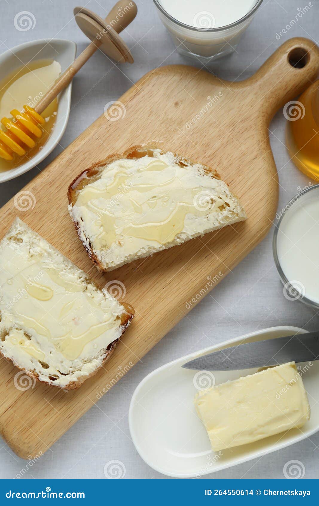 Slices of Bread with Butter, Honey and Milk on White Table, Flat Lay