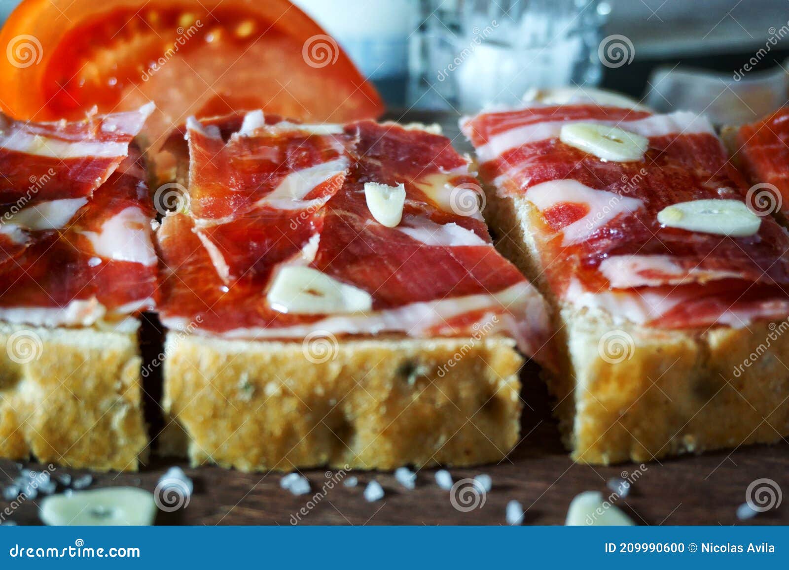 slices of bread with ham, oil, tomato and garlic