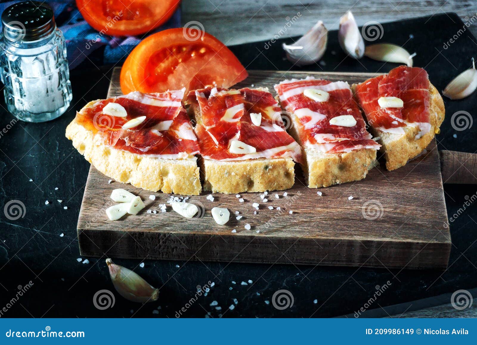 slices of bread with ham, oil, tomato and garlic