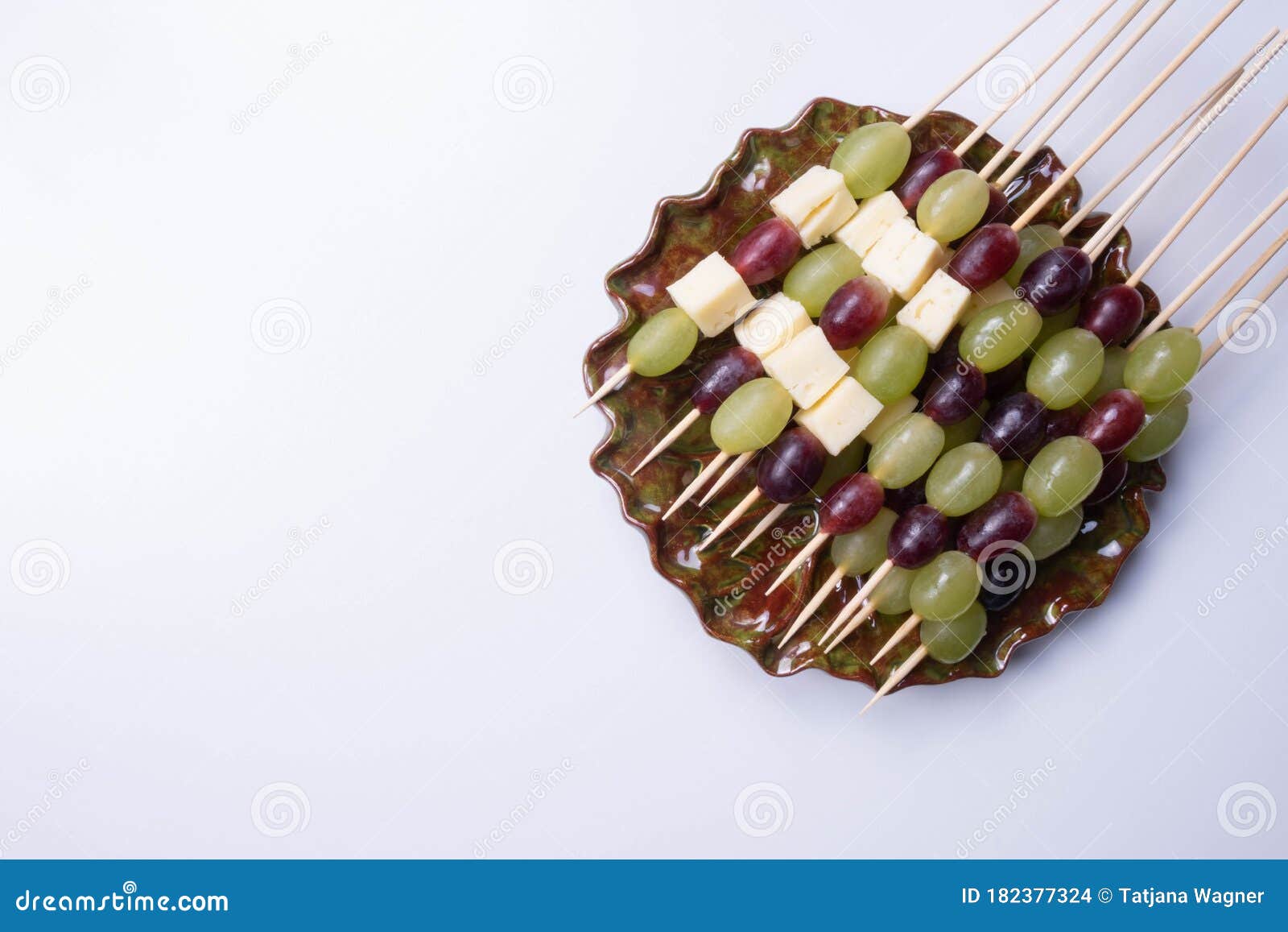 Slices of Cheese and Grapes on a Stick in a Plate on a Table Stock