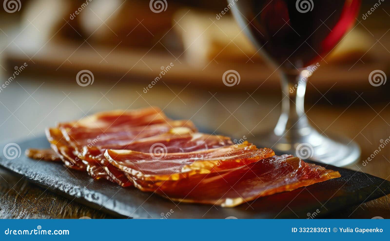slices of cured meat on a slate board beside a glass of red wine in a warm setting