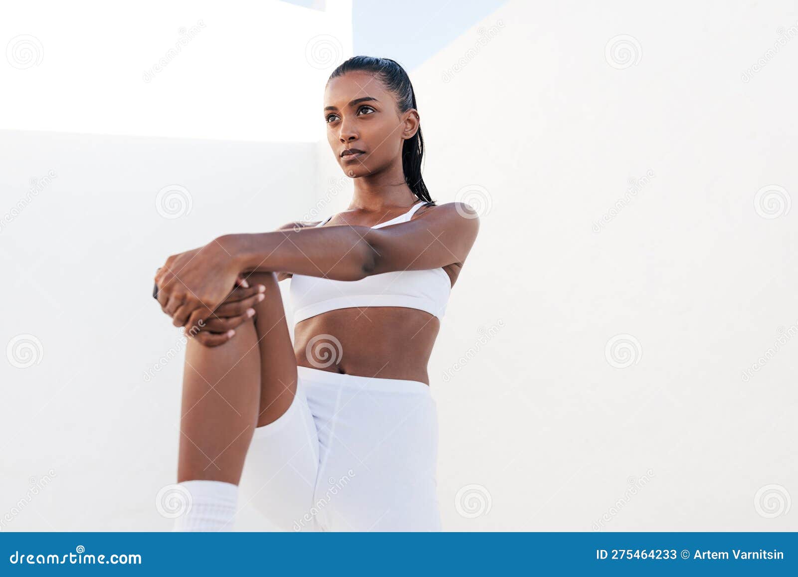 Portrait of a slim female in white fitness attire standing in an