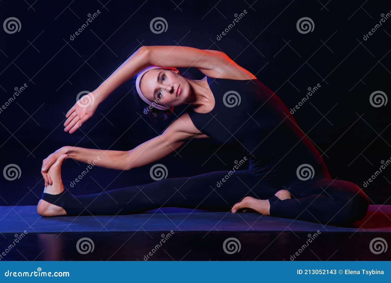 A Slim, Fit Girl is Doing Stretching Sports on a Black Background in ...