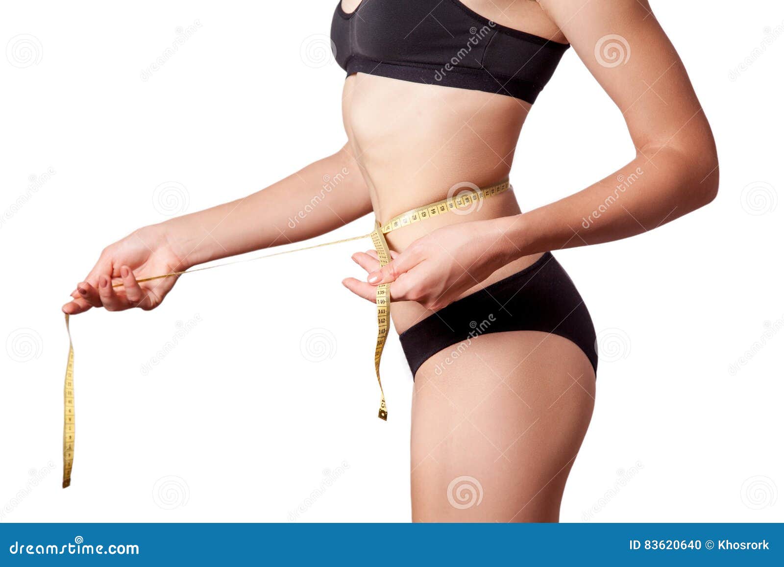 Photo of Young slim woman measuring her waist with a tape