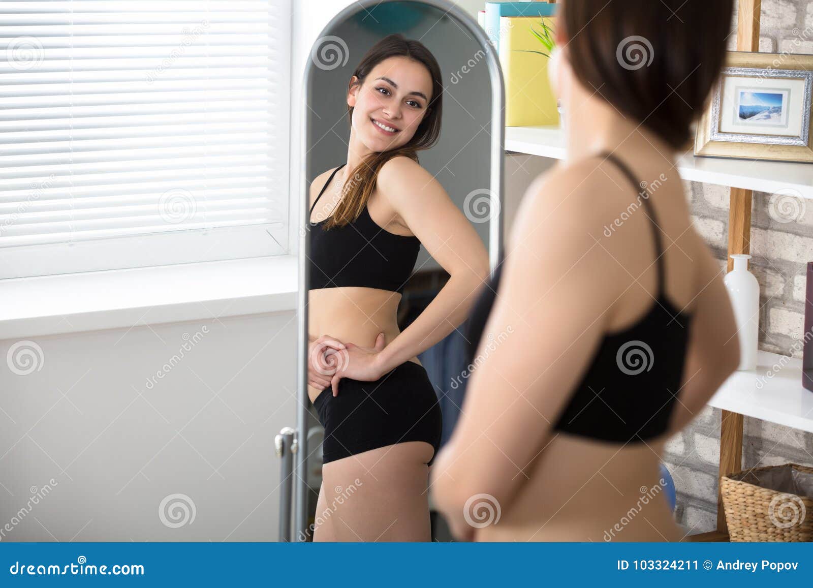 slim woman looking in mirror