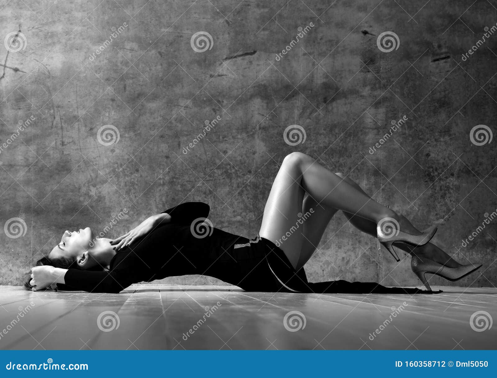 slim woman lying on a floor sexy with gorgeous legs on dark wall background. black and white