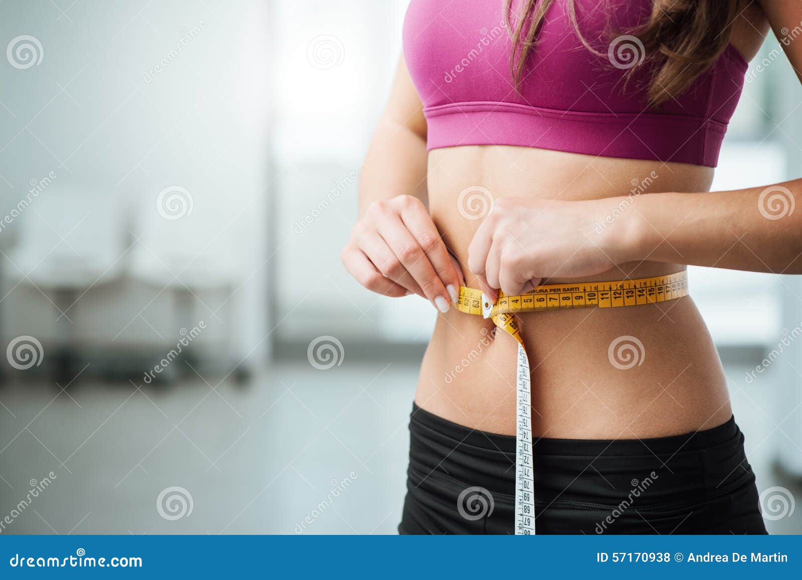 slim woman measuring her thin waist