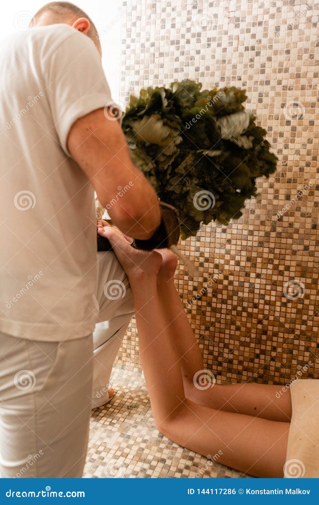 Slim Woman In Bath Is Getting Steaming Massage With Hot Oak Leaves Brooms In Steam Room Stock