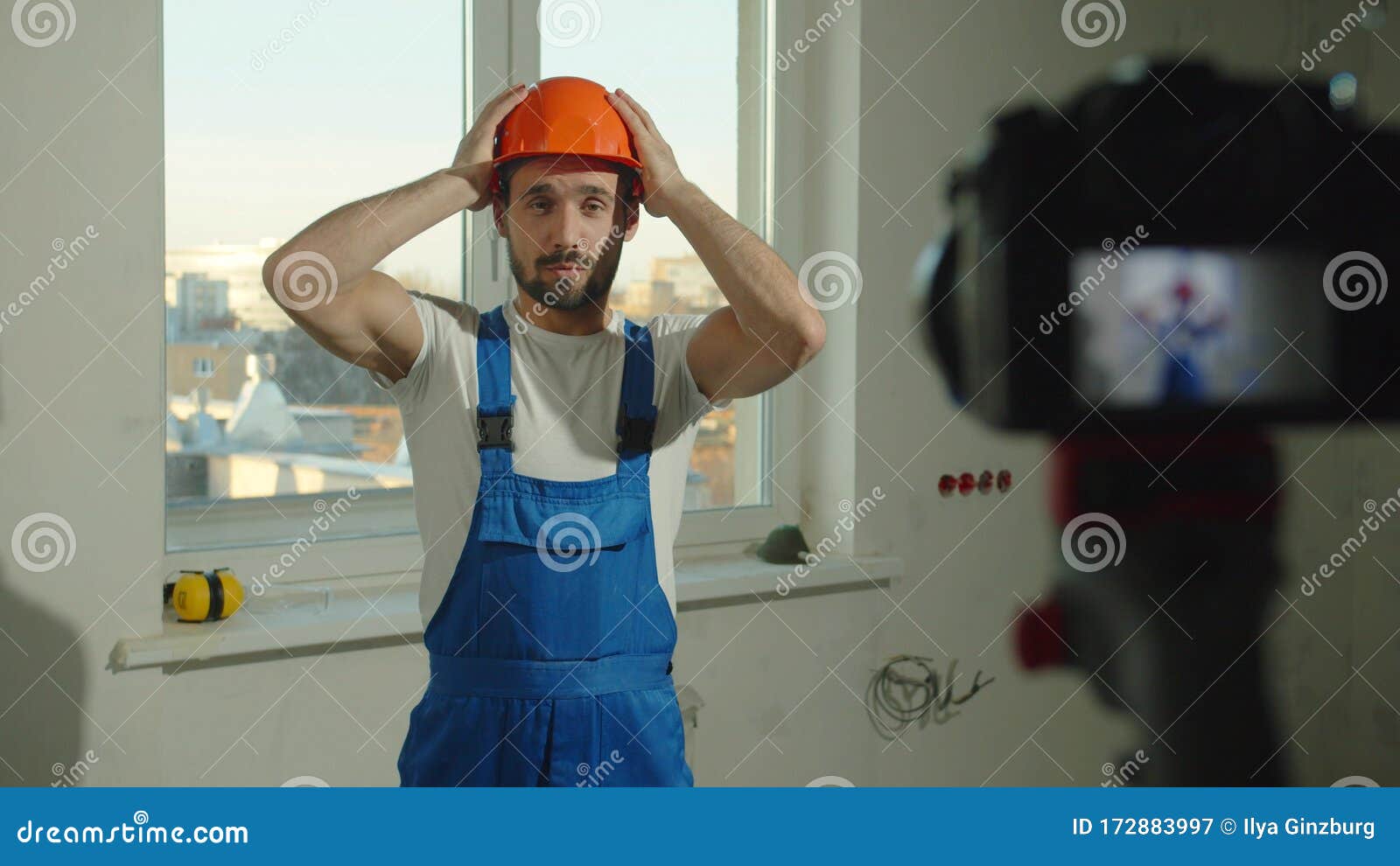 Slow Motion, Builder Puts on Helmet and Talks on Camera Stock Image