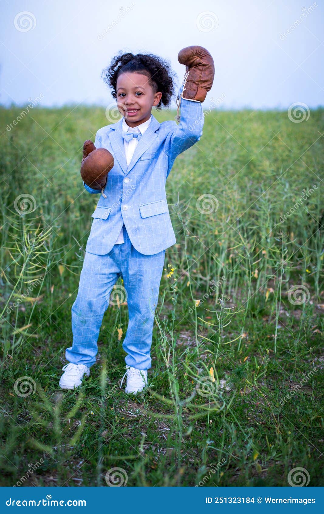 Small Black Boy in Blue Suit with Boxing Gloves Standing in a Field