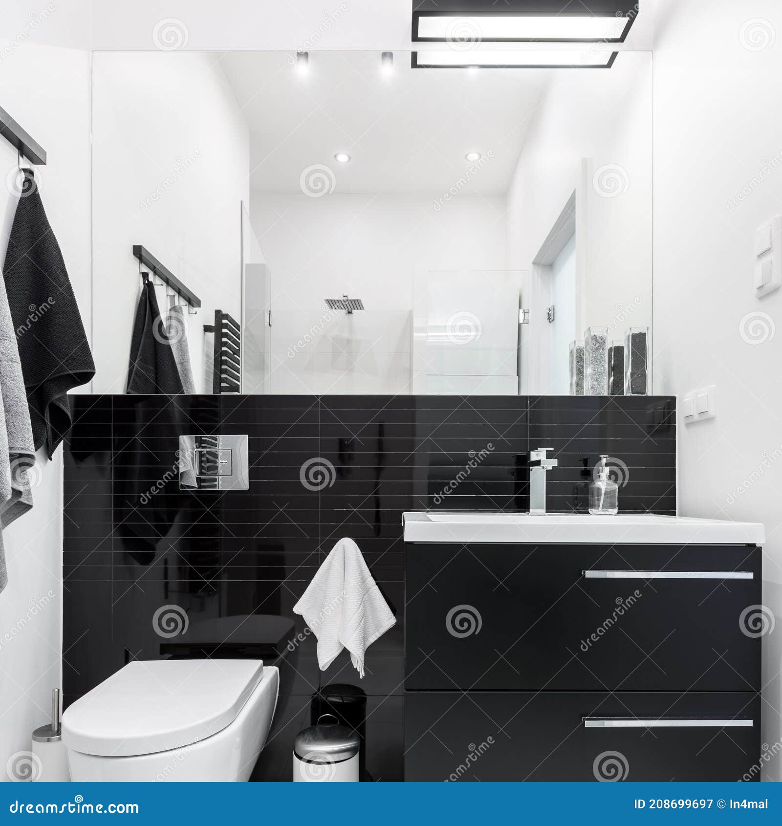 Interior design of contemporary toilet room with round mirror lamp small  black sink white walls with beige small square tiles Stock Photo - Alamy