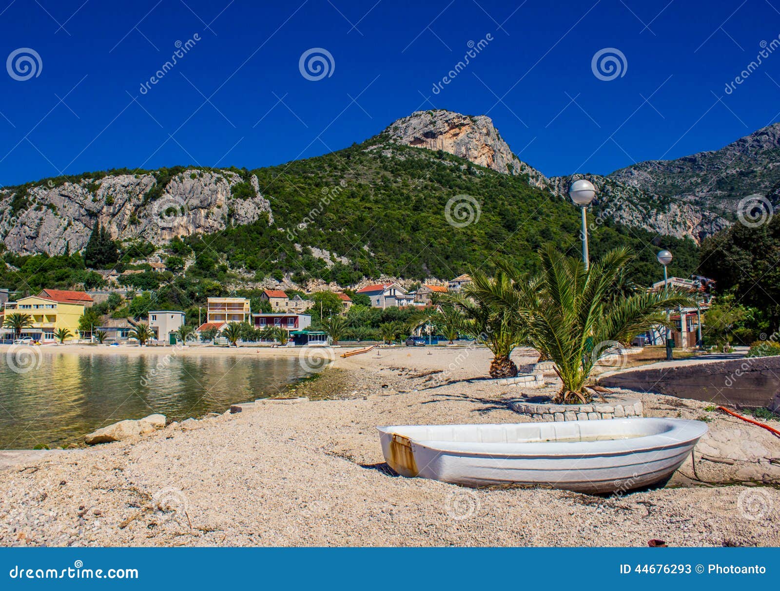 Small boat on a beach with houses and mountain in the background