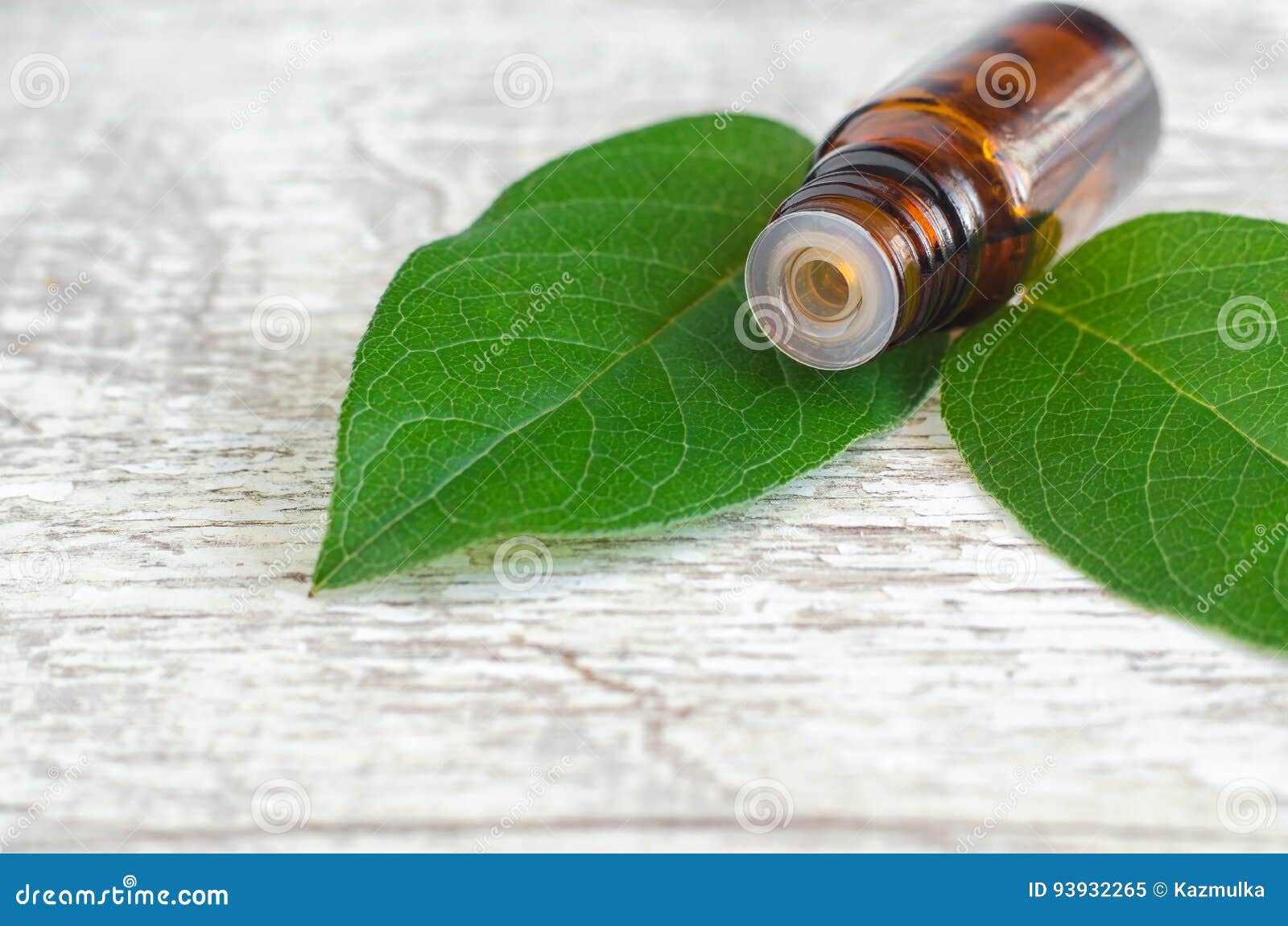 Small Bottle of Essential Oil and Fresh Leaves on the Wooden Background ...