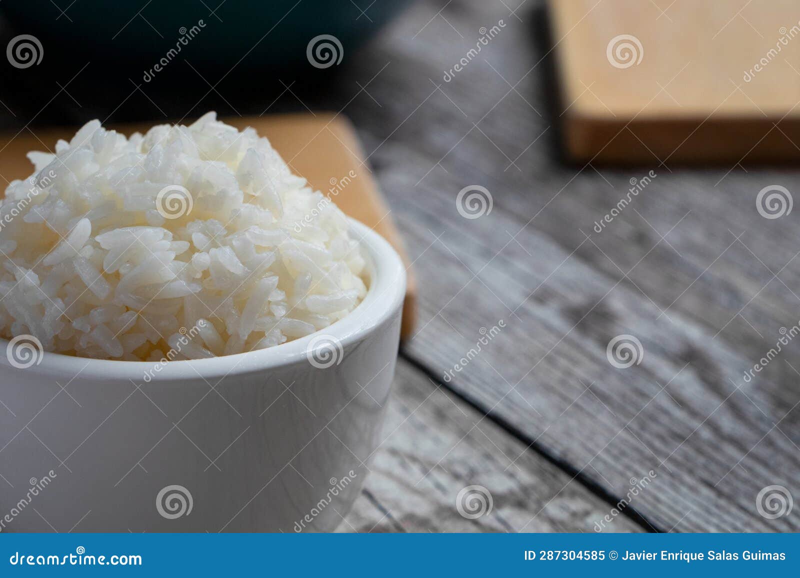 small bowl with rice in the foreground and some kitchen utensils