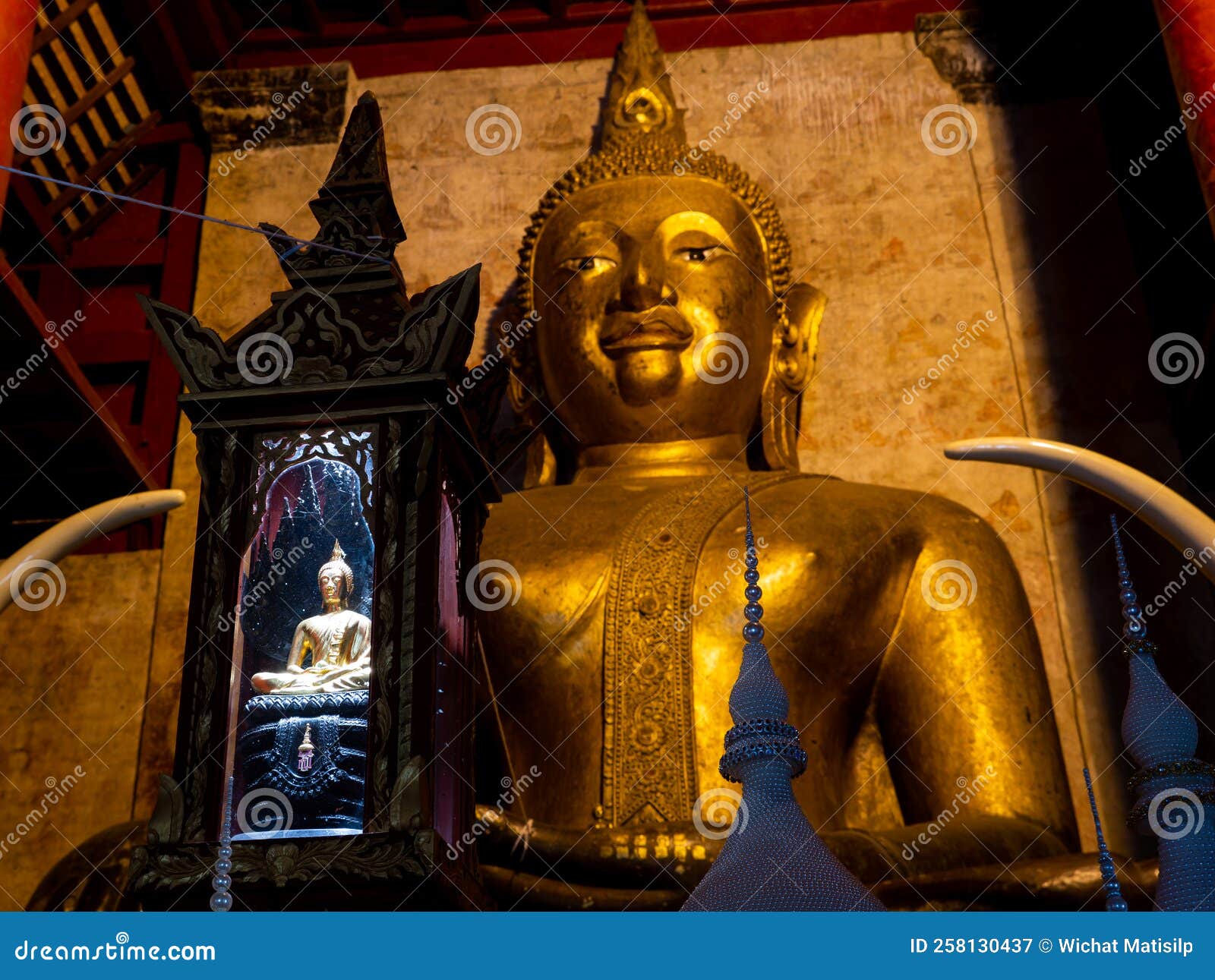 Small Buddha Statue Siting in Front of the Large Buddha Sitting in the