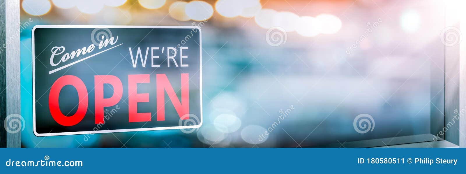 small business store front with `come in we`re open` sign hanging on window