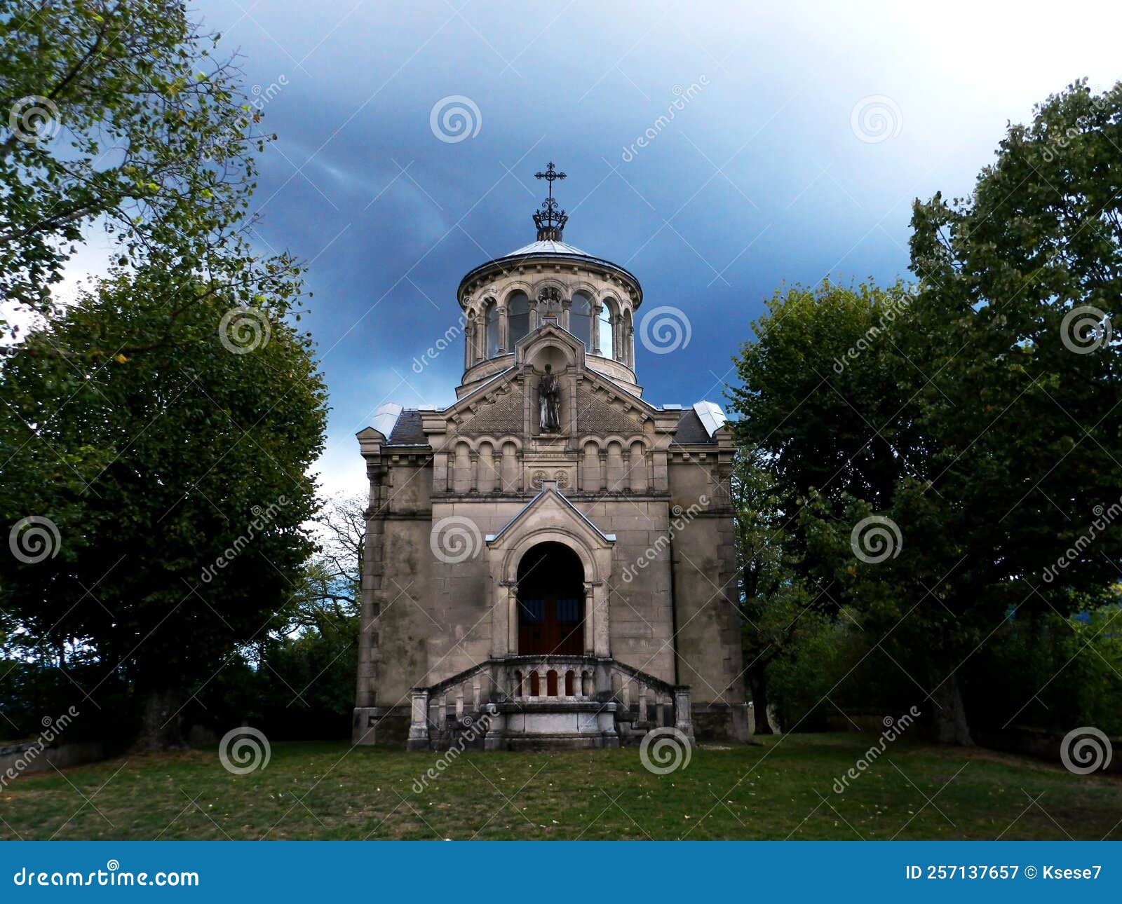 gloomy view of the sainte-beatrix chapel against a dark evening sky with heavy rain clouds