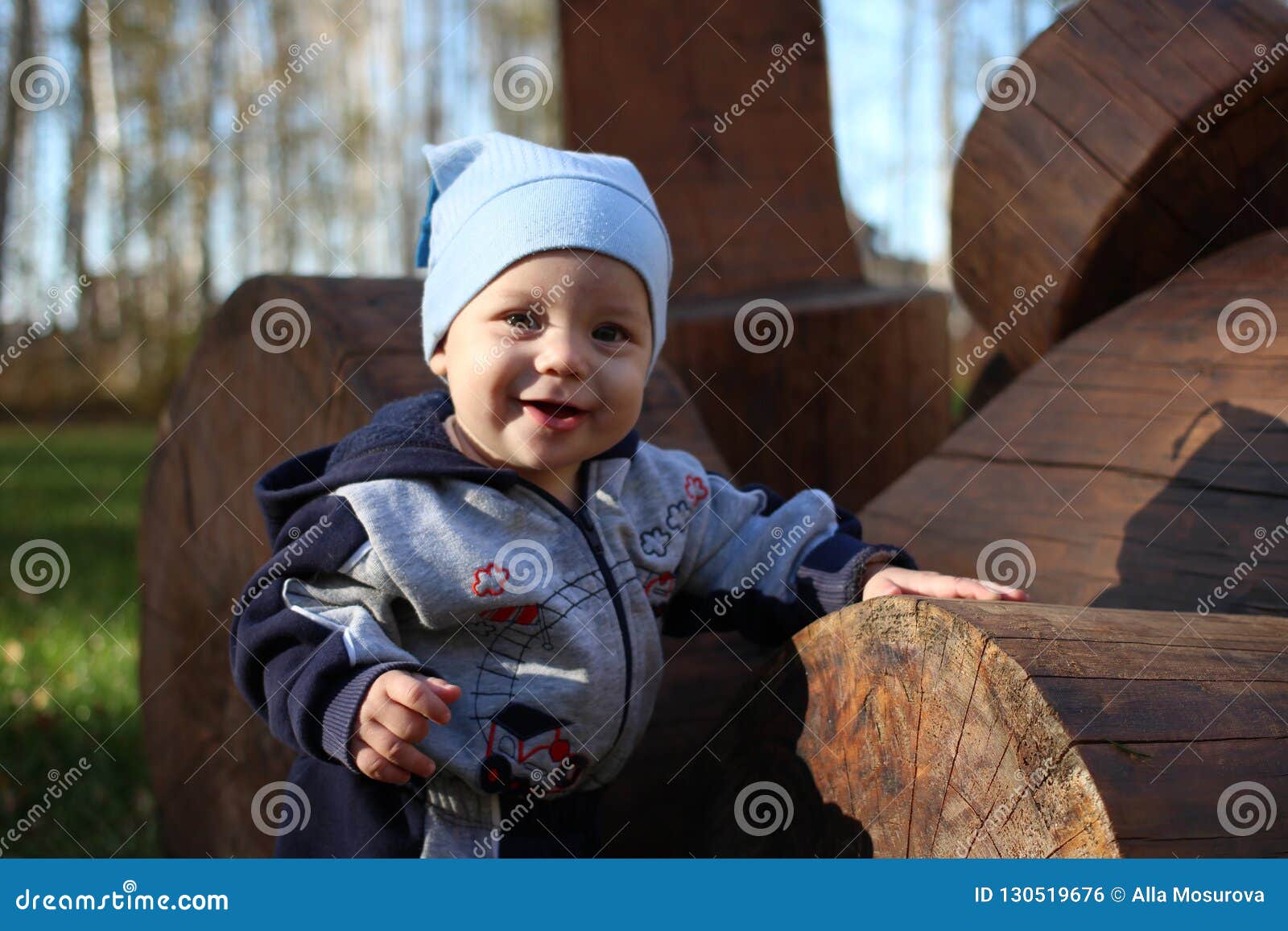 A Small Child Clings To Wood Logs of a Smiling Summer in the Park Stock ...