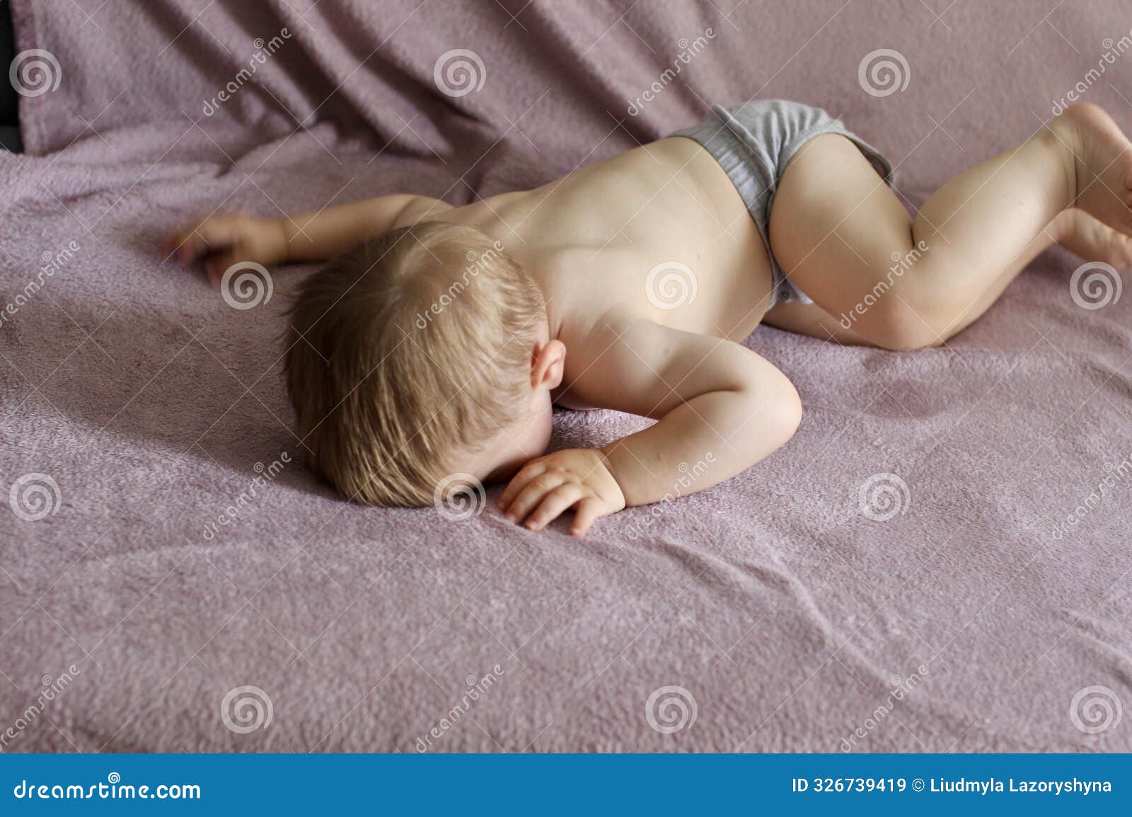 a small child is offended and cries lying face down in a blanket