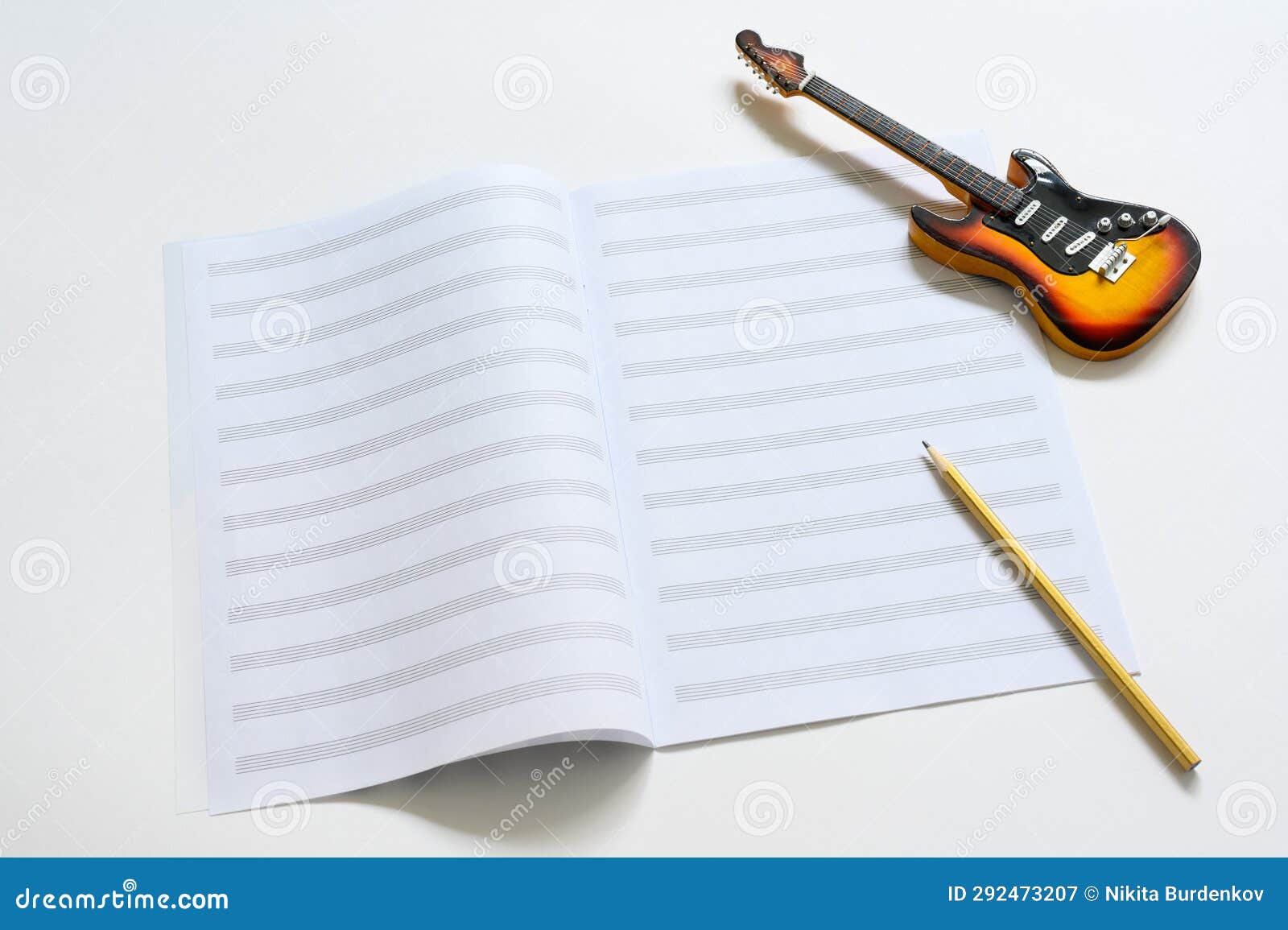 A Small Figurine of an Electric Guitar and a Blank Notebook. Music