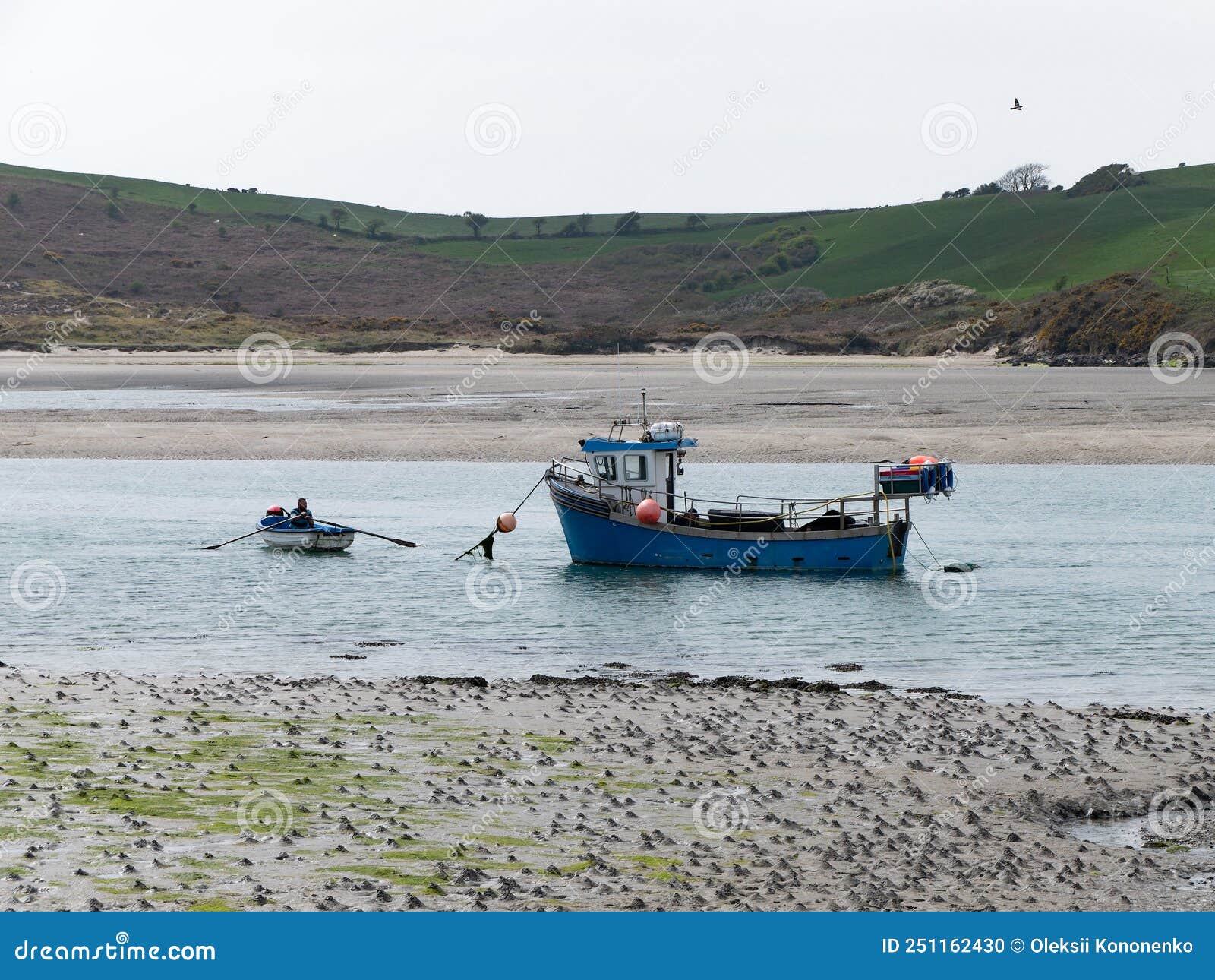 A Small Fishing Boat Moored in Shallow Water. One Man in a Rowing