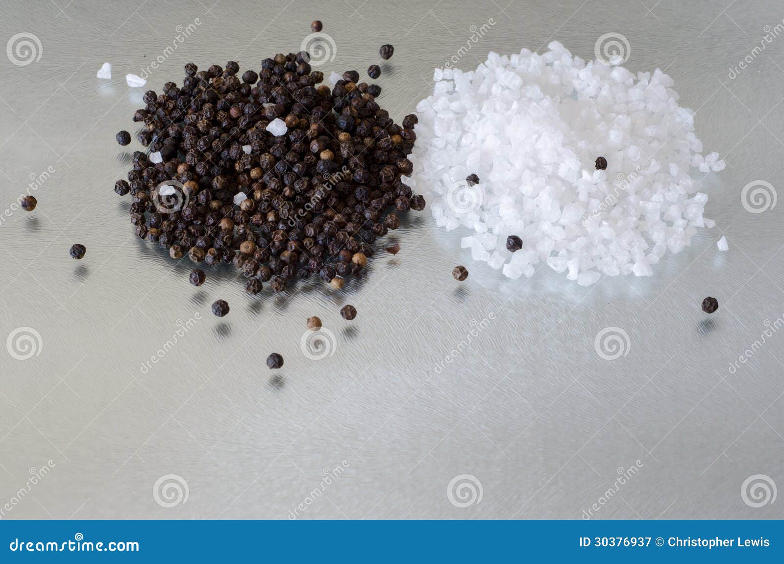 a small heap of seasalt and peppercorns on reflective surface