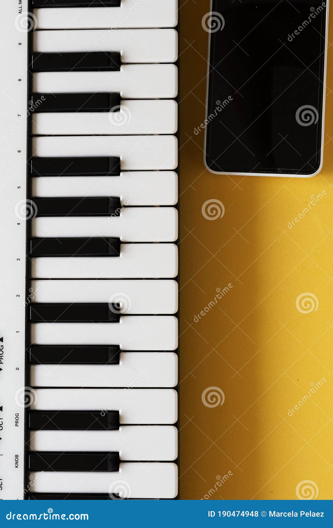 Small MIDI Controller Piano on Yellow Background with Cell Phone