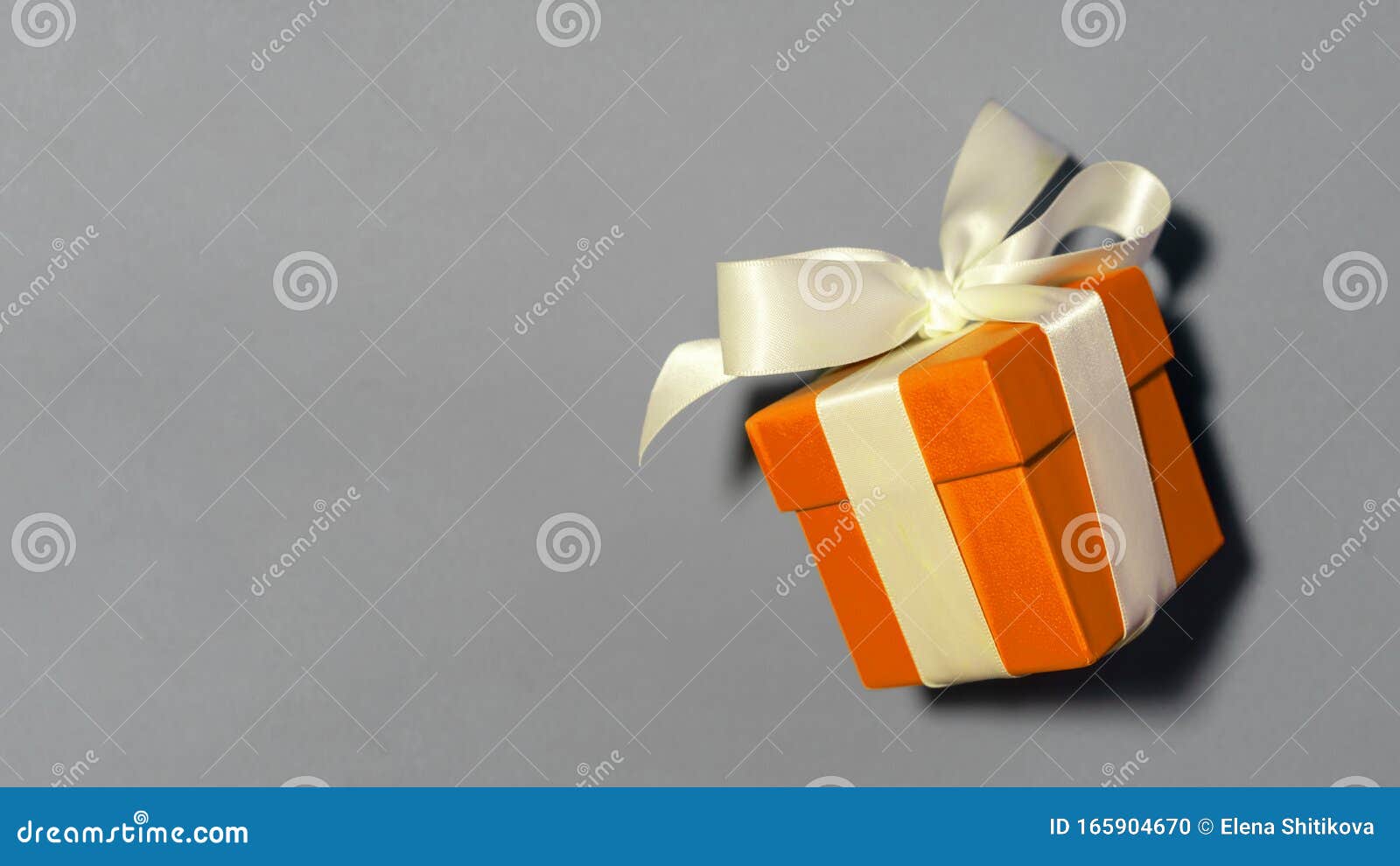 Small Orange Gift Box Tied Up with a Bow Ribbon on a Blue Background. Stock  Photo - Image of orange, christmas: 165904670