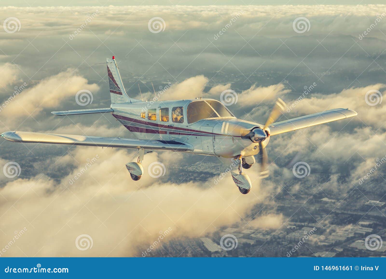 small single engine airplane flying in the gorgeous sunset sky through the sea of clouds above the spectacular mountains