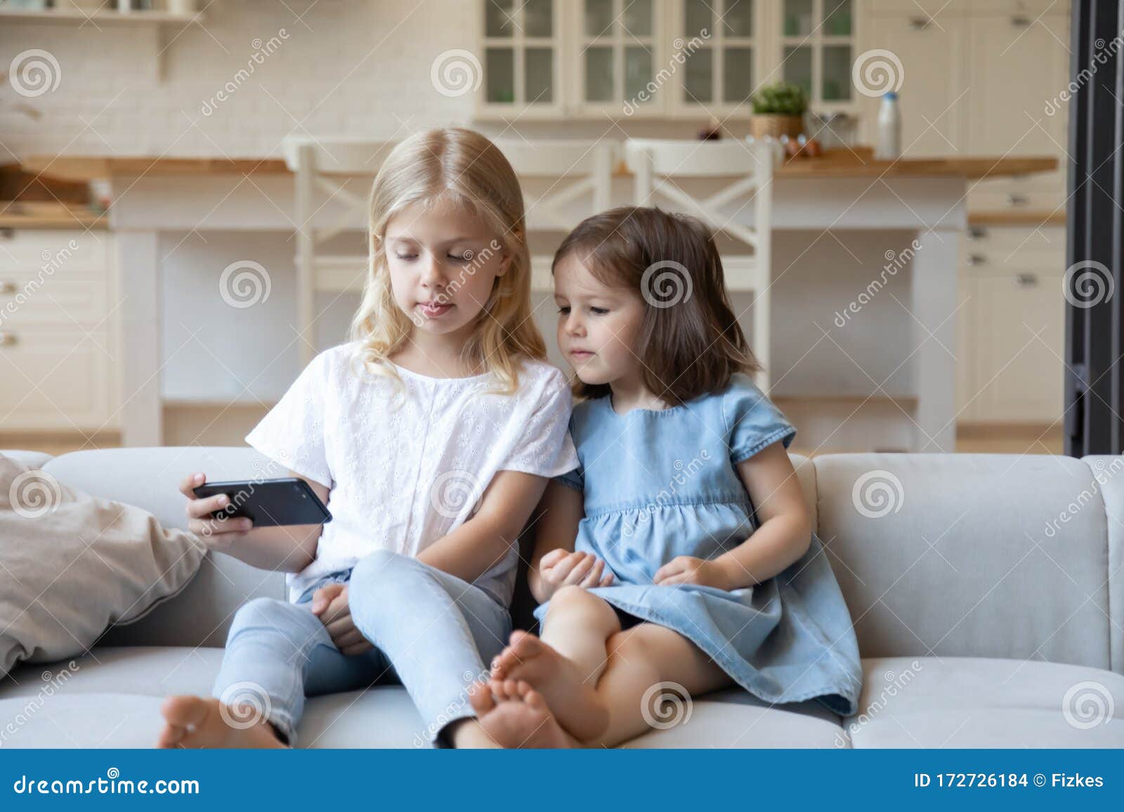 Little Sisters Watch Video on Cellphone at Home Stock Photo - Image of ...