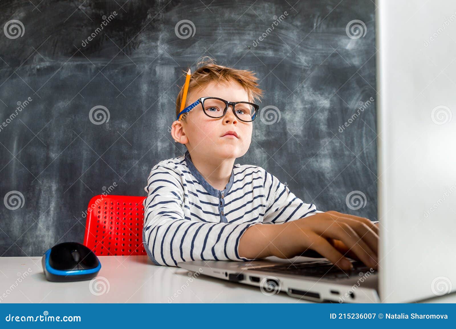 Smart Nerd Kid Boy with Laptop Computer. Student in Glasses is