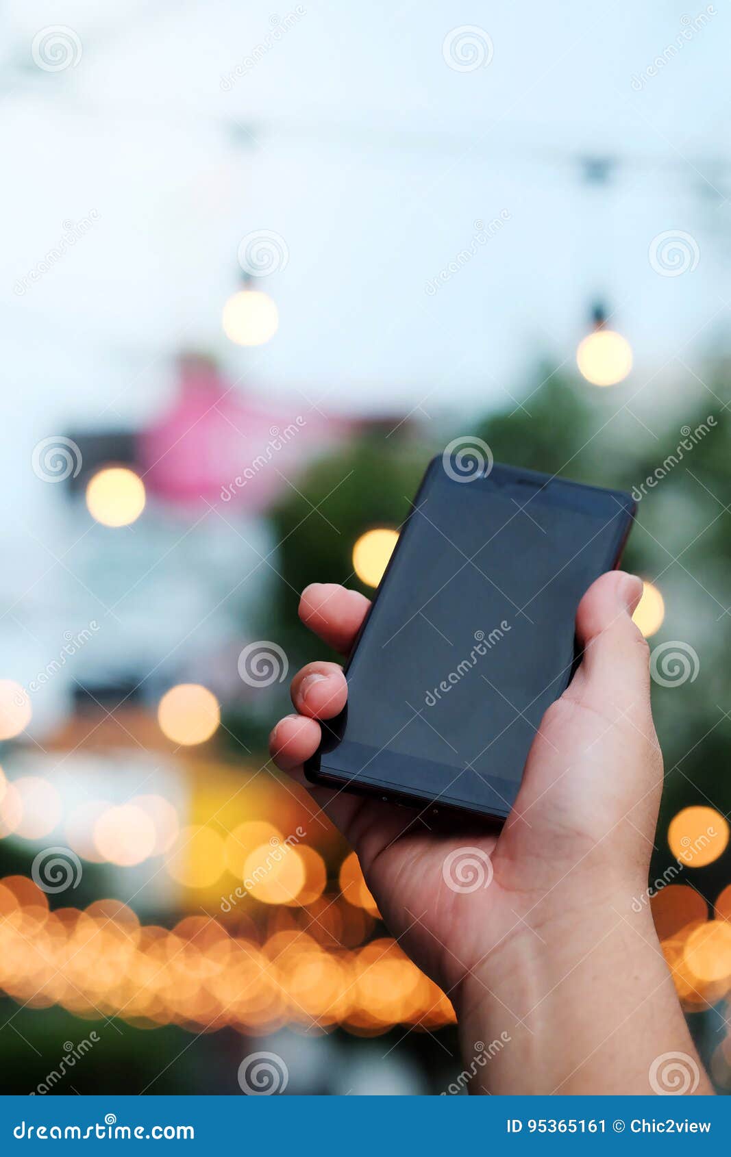 Smart Phone In Hand With Bokeh In Park Background And Have Some Space