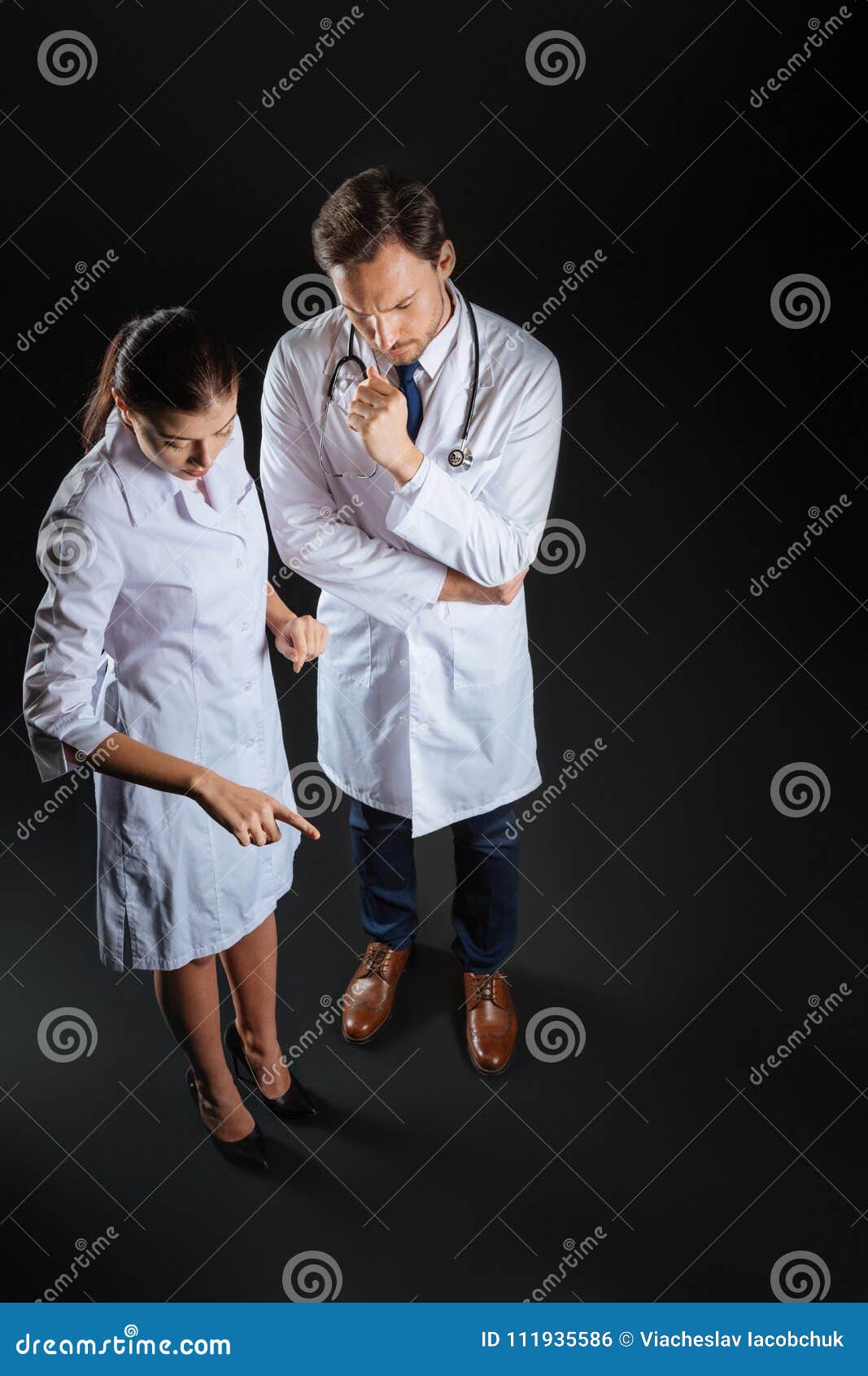 Smart Qualified Nurse Standing and Working with Her Partner. Stock