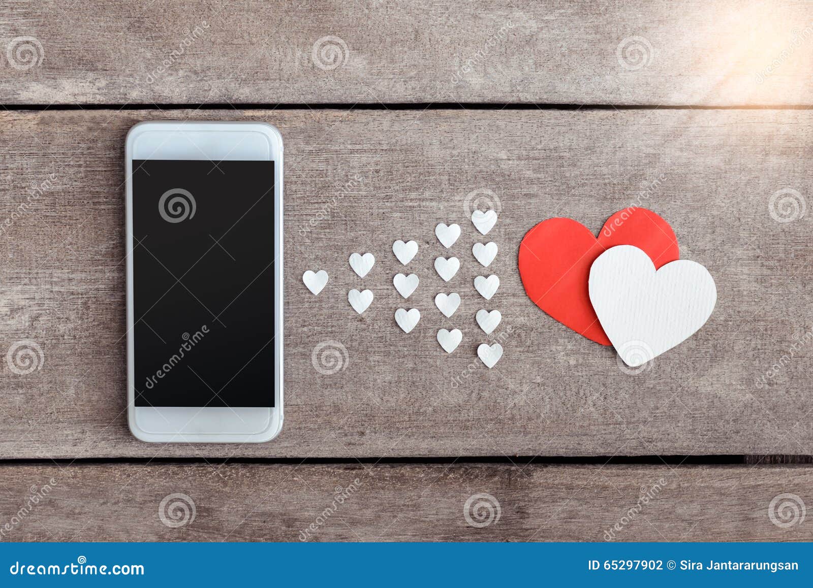 smartphone and hearts paper on wooden background