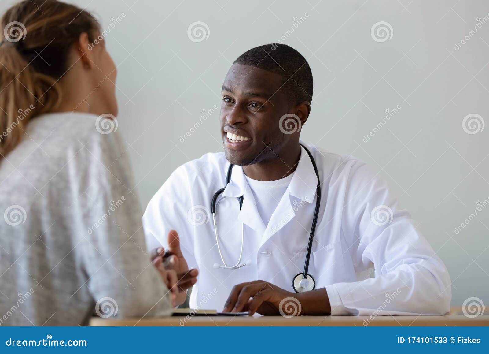 smiling african american doctor talking to patient at visit