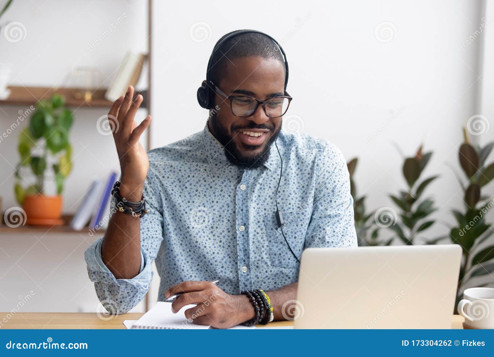 smiling african american employee in headphones using laptop