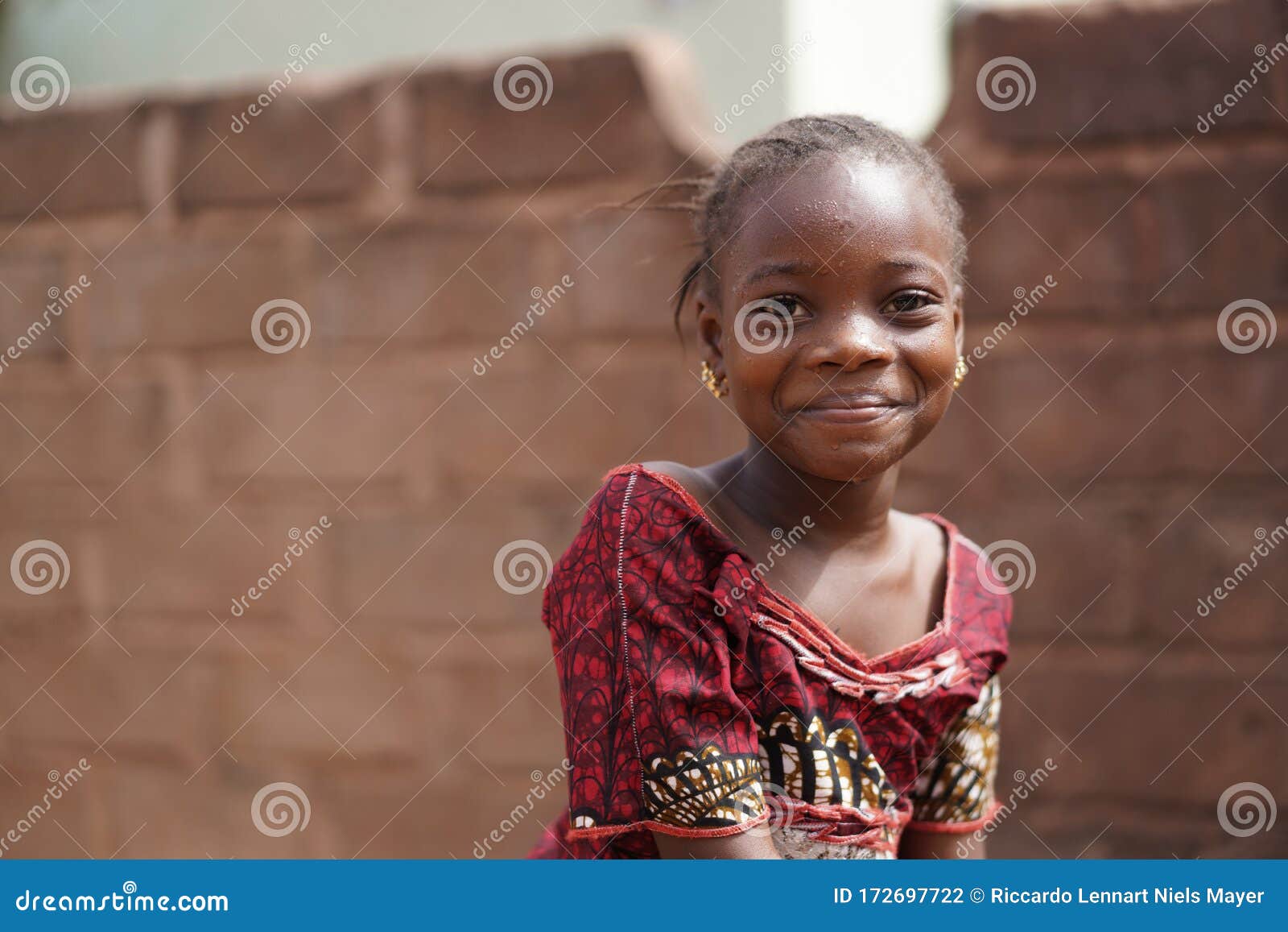 smiling african girl with a wet face after having taken a sip from the water borehole