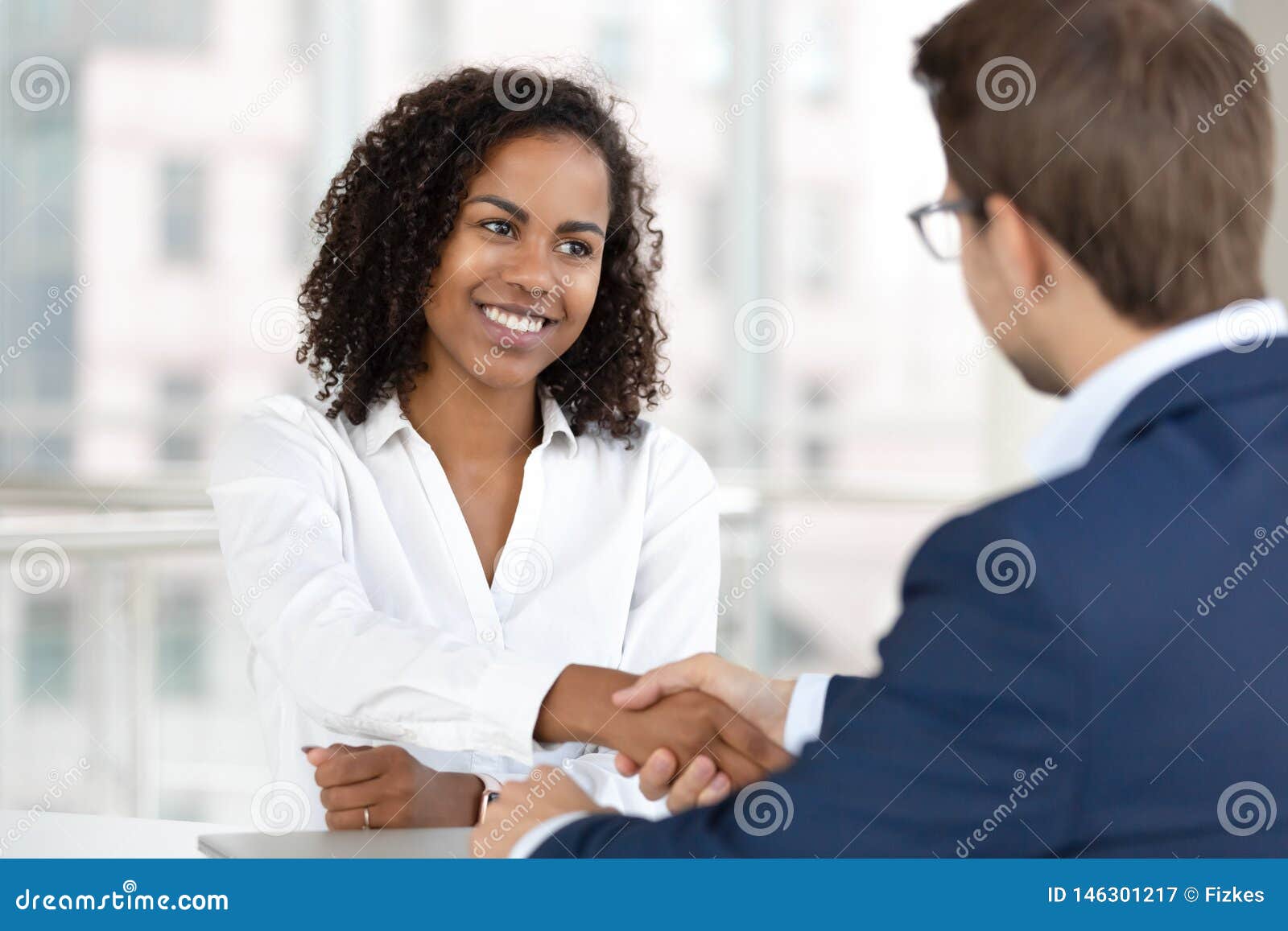 smiling african hr manager handshake hire candidate at job interview