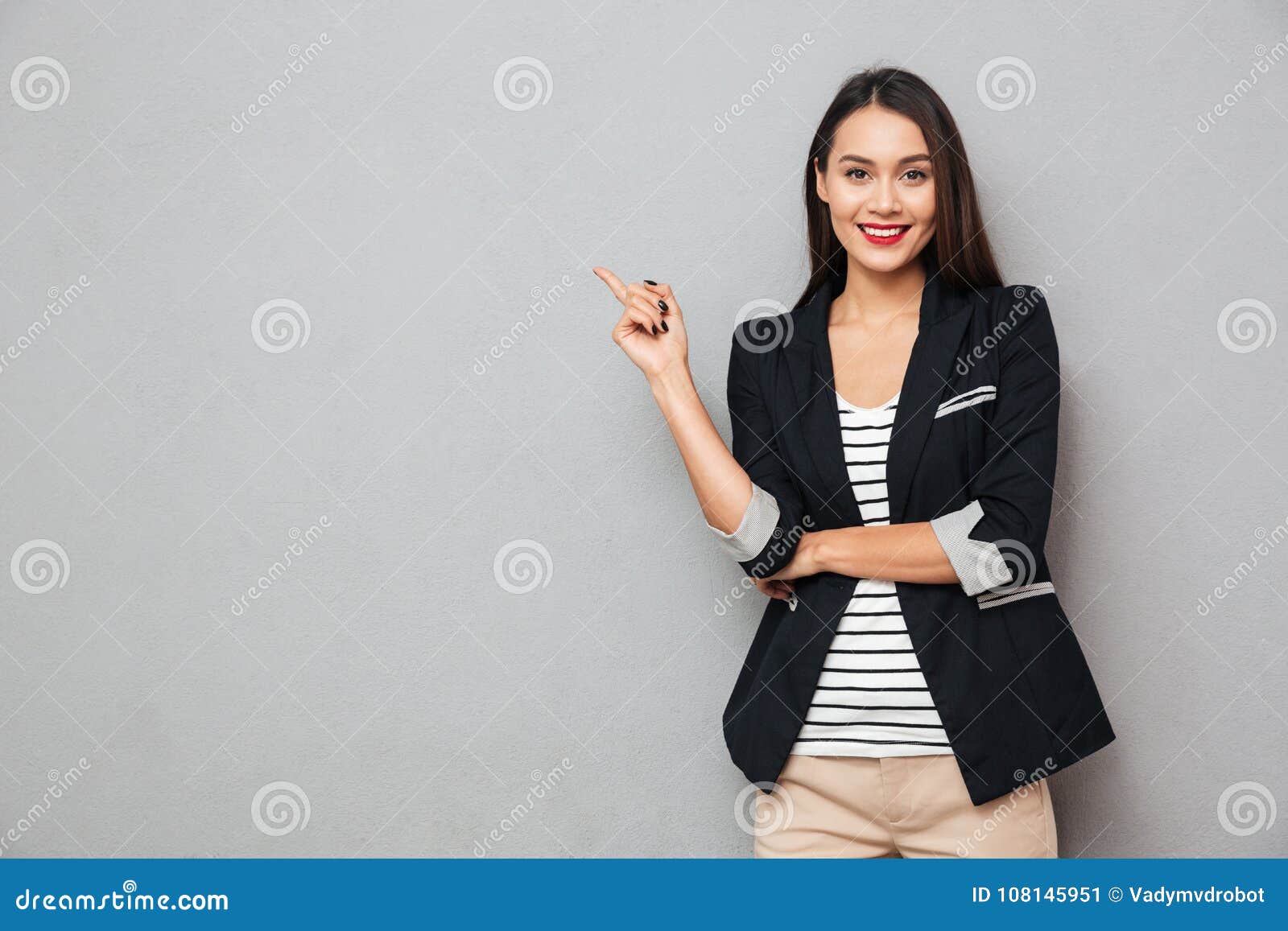 smiling asian business woman pointing up and looking at camera