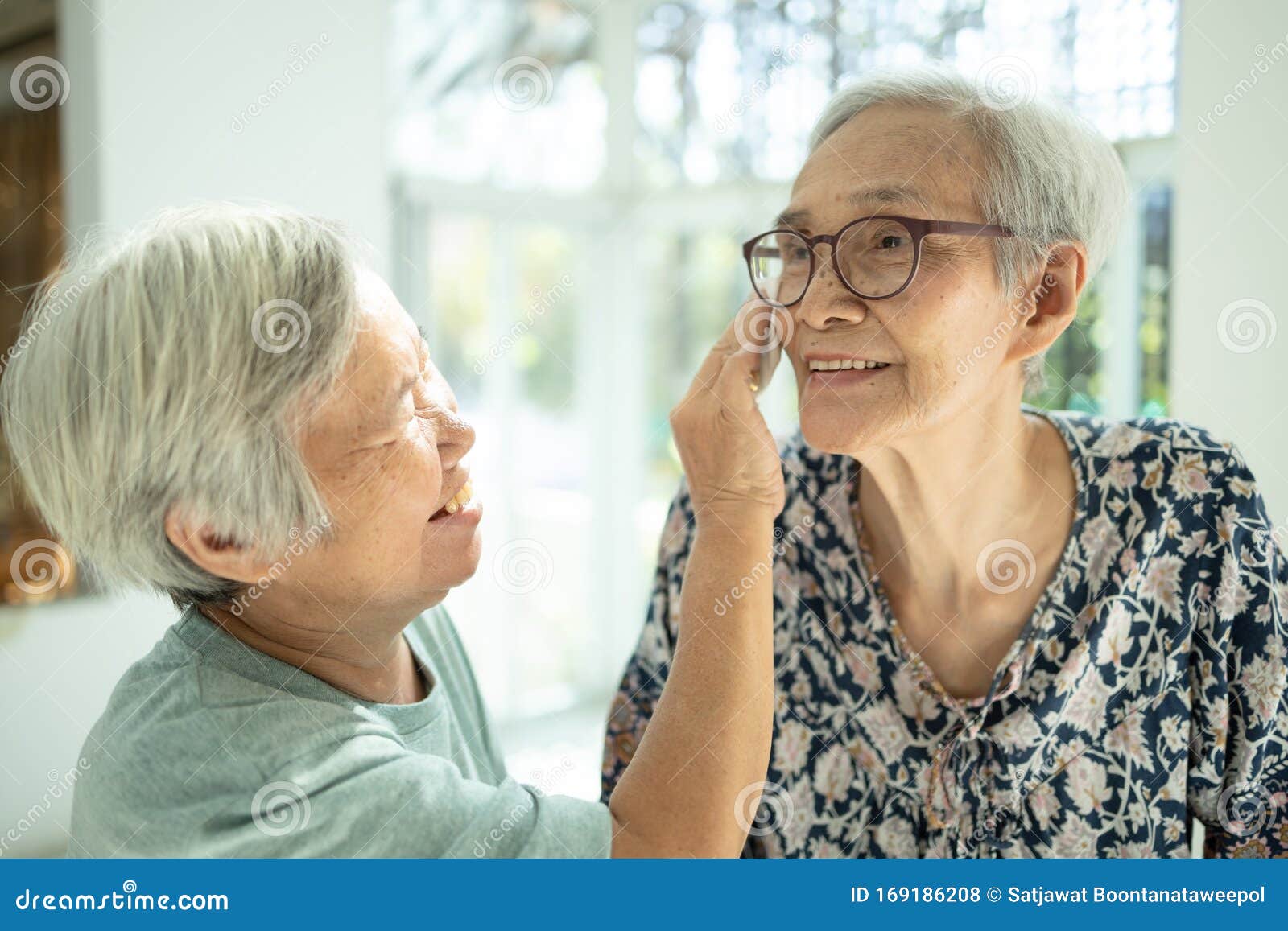 smiling asian female elderly person wipe sweat on the skin face of the senior sister and talk happily,old people visited her  aged