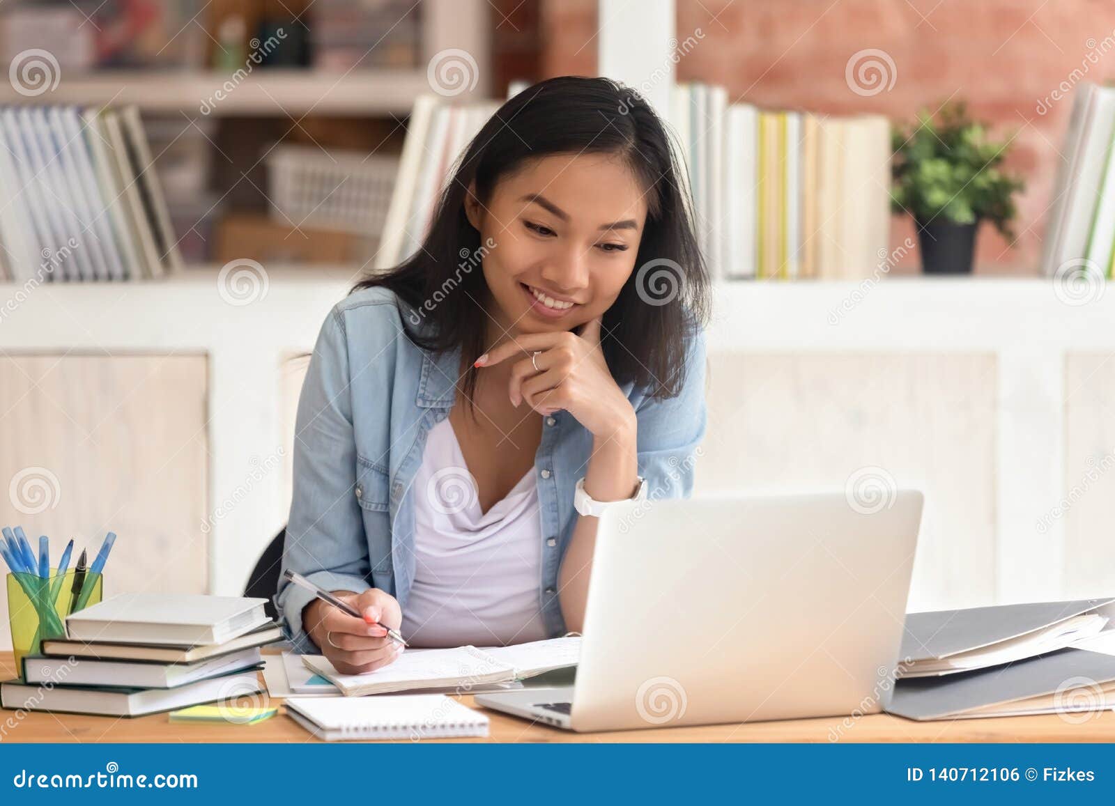 smiling asian girl student study in library with laptop books