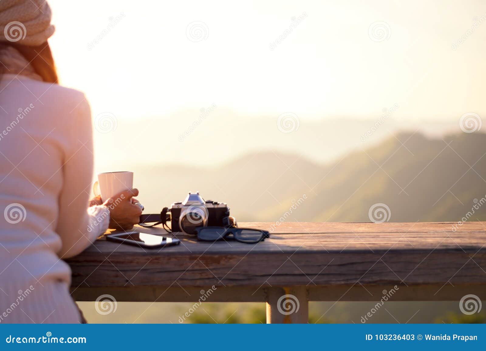 smiling asian woman drinking coffee and tea and take a photo and relax in sun sitting outdoor in sunshine light enjoying her warm