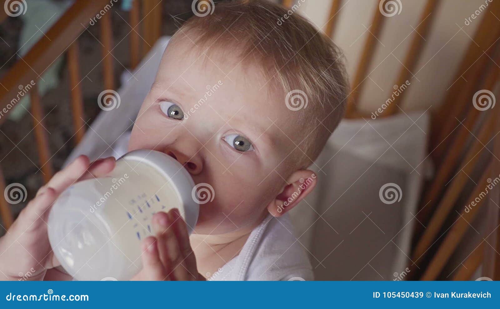 smiling baby boy standing and drinking milk from a bottle stock
