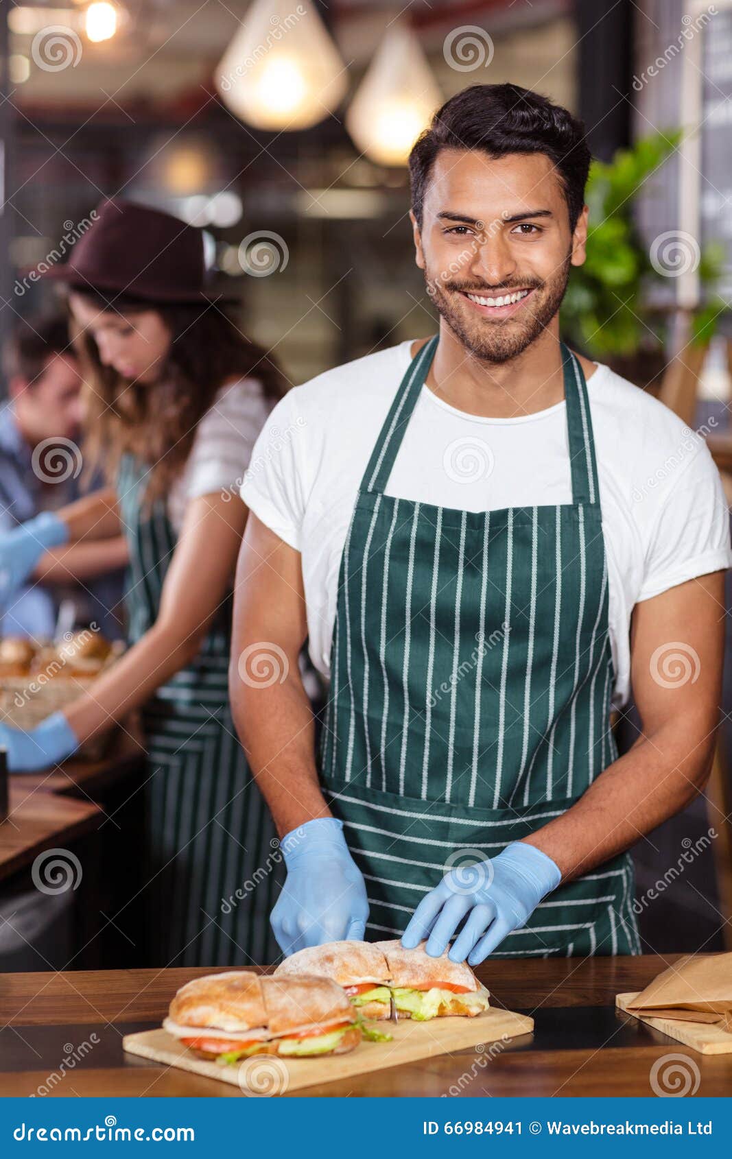 smiling barista cutting sandwich